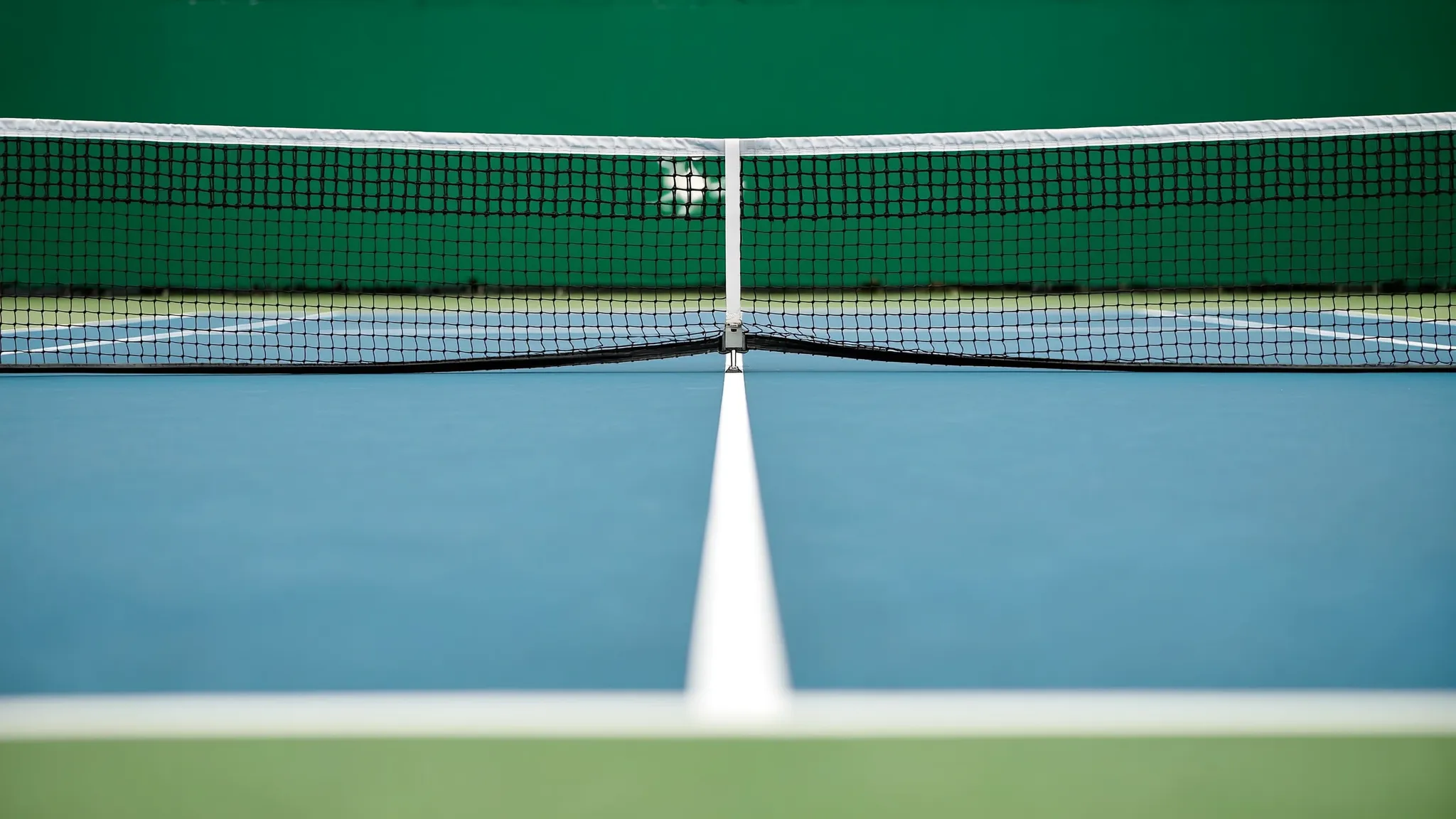 A tennis court at the All England Club with the Wimbledon net post visible in the foreground